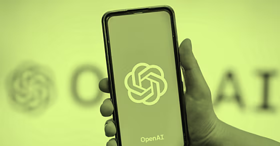 Visual of a hand holding a phone showing on the screen ChatGPT logo